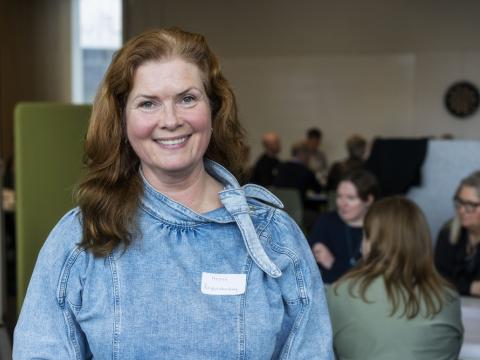 Woman smiling with people in the background.