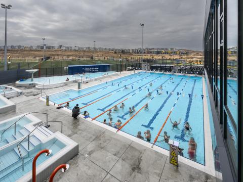 Dalslaug swimming pool, photographed from the building looking down over the pool area. People in the pool. Overcast conditions outside.